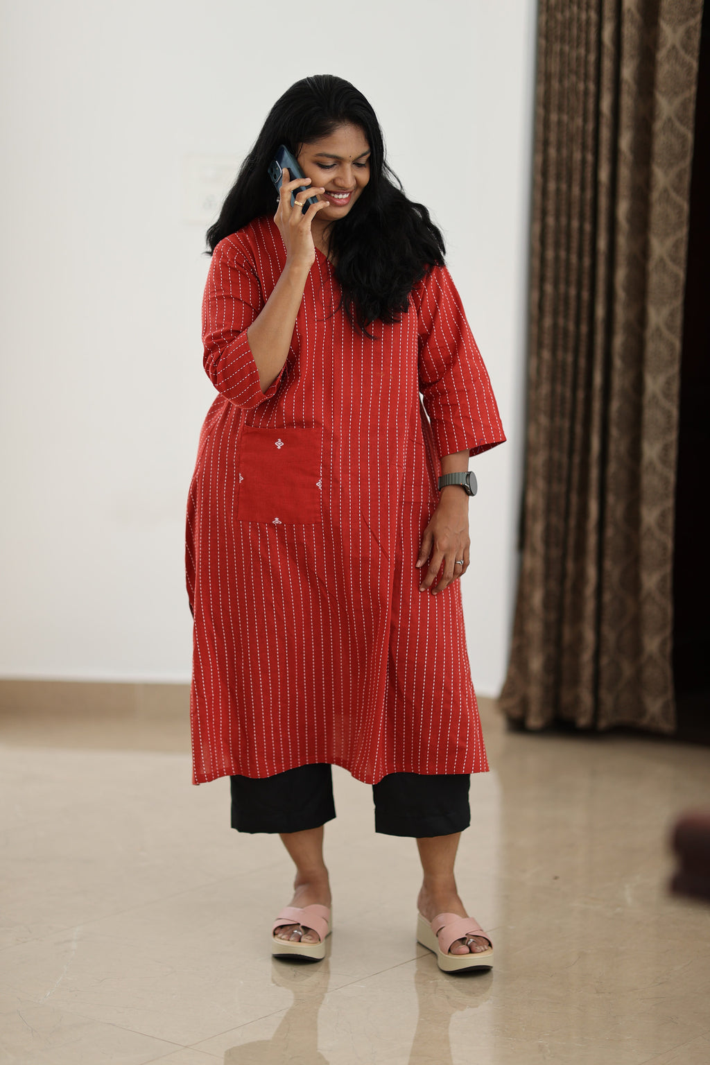 30+ woman using a phone in a red office kurta with statement pocket