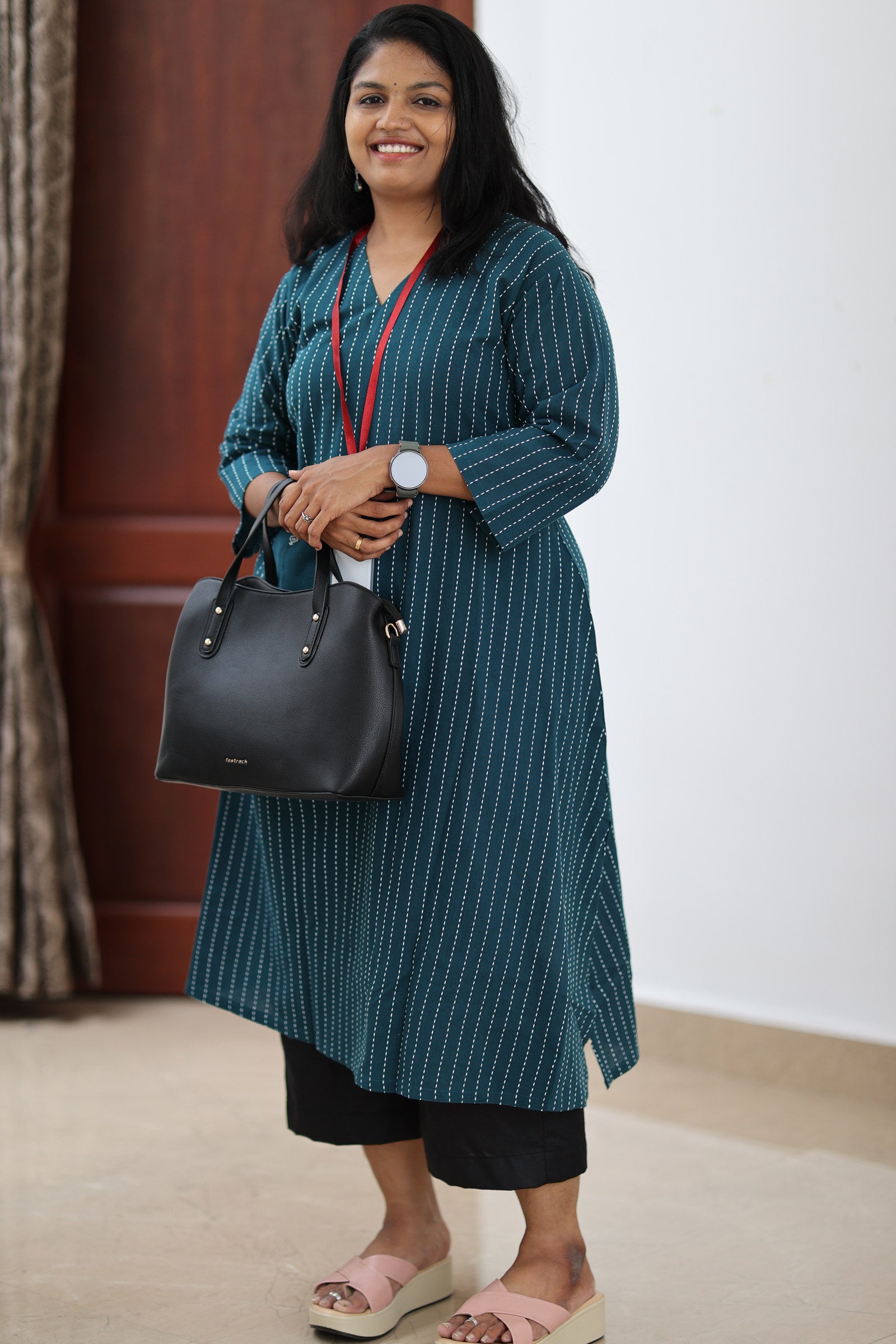 30+ woman wearing teal striped office kurta with black trousers and work bag