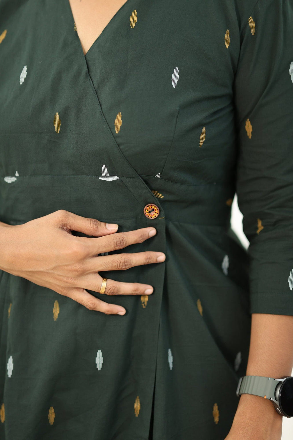 Wooden button at the waist and the box pleat below it
