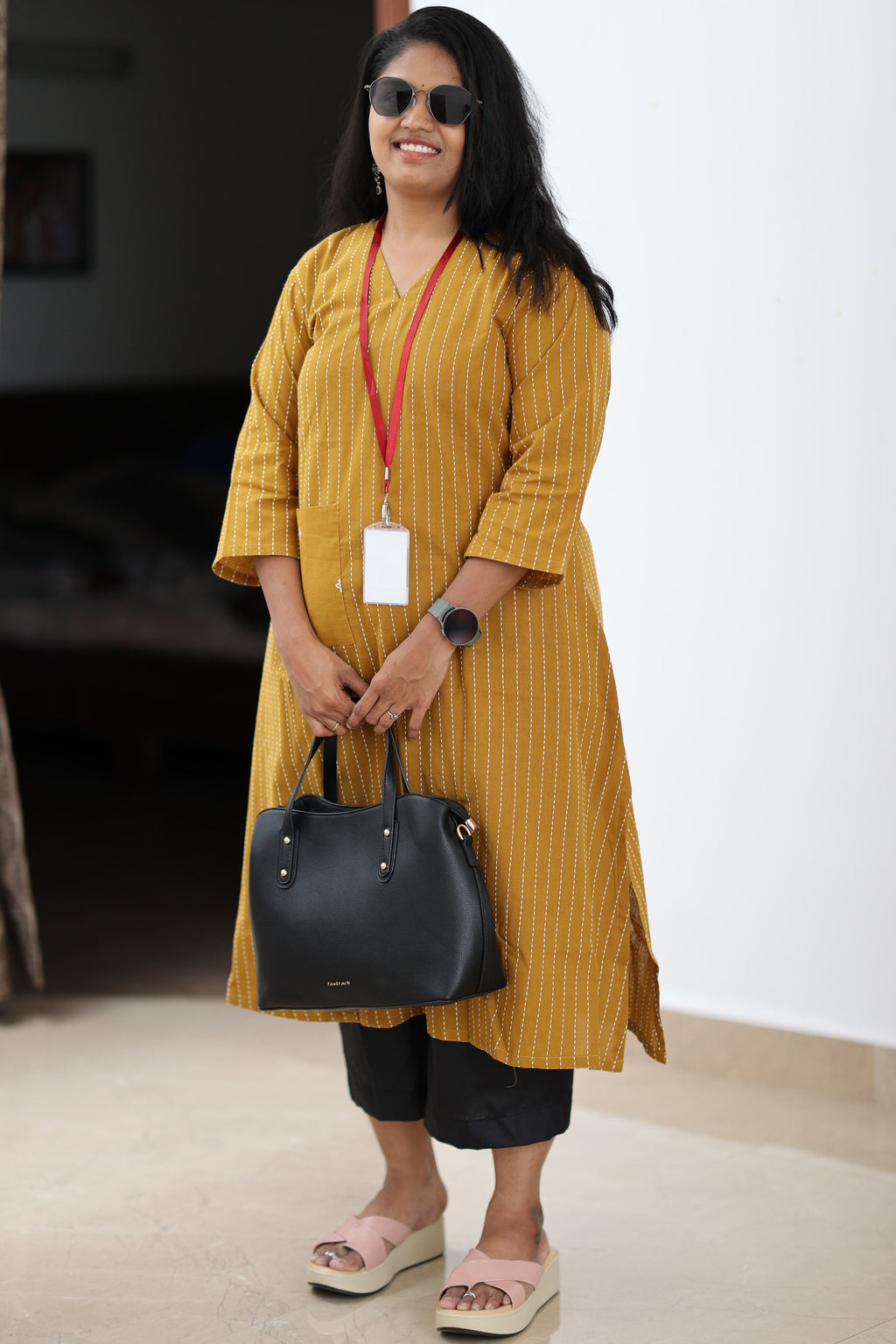30+ woman wearing mustard striped office kurta with black trousers and work bag