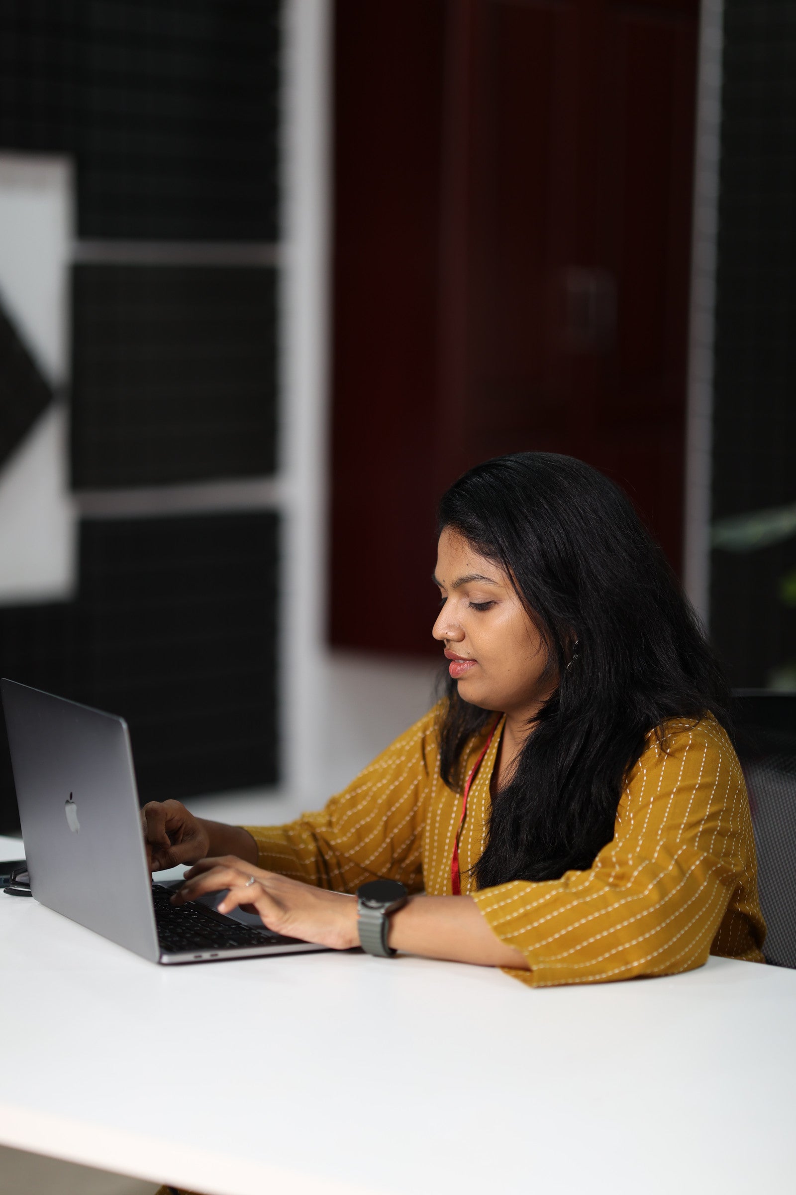 30+ woman working on a laptop in mustard striped office kurta