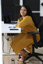 30+ woman seated at an office desk in mustard striped kurta